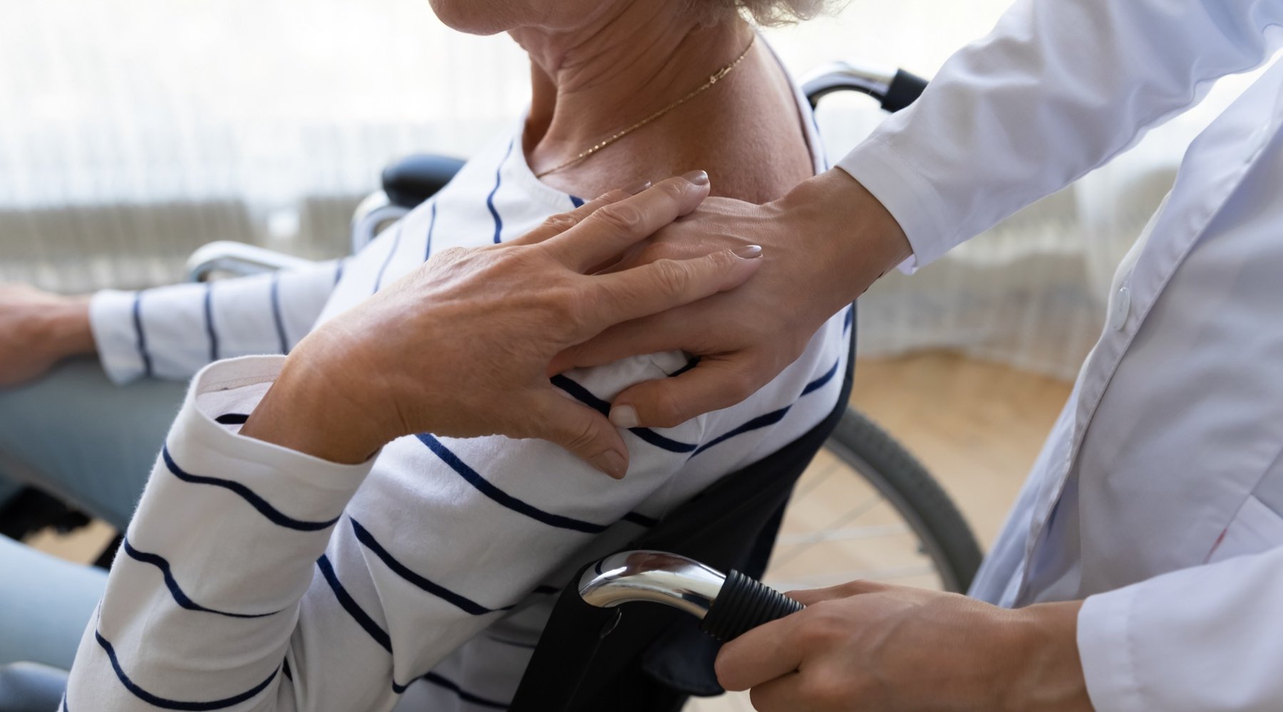 persona che mette le mani sulla spalla di una persona anziana